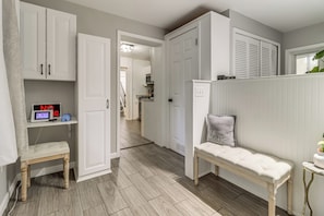 A hallway with a bench, a white door, and a wall-mounted thermostat.