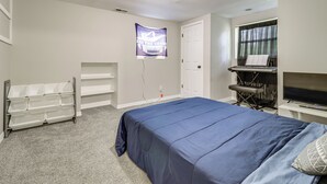 A bedroom with a bed, a TV, a shelf, a window with curtains, and a wall-mounted poster. - 4 Mi to Utoledo! Cozy Family Home (Toledo)