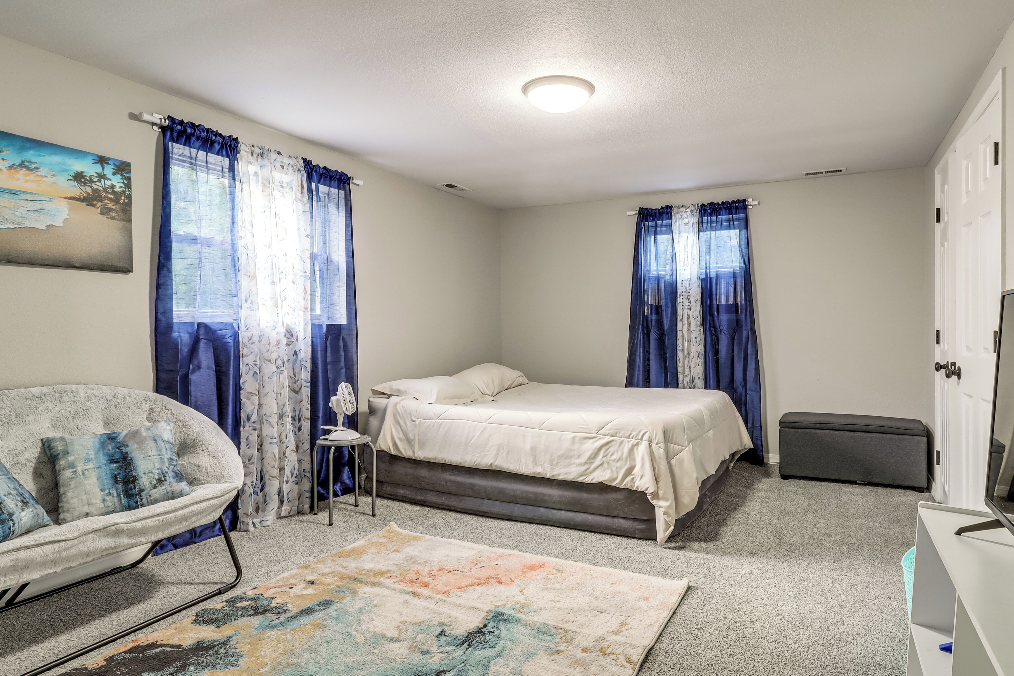 Un dormitorio con una cama, una silla, una mesita, un banco y un televisor.