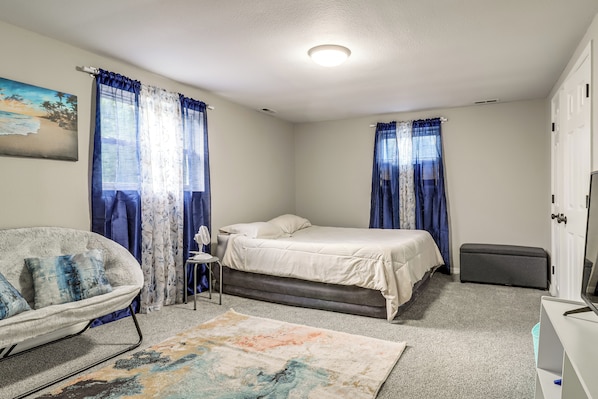 A bedroom with a bed, a chair, a small table, a bench, and a television.