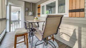 A covered patio area with a table and two chairs, a potted plant, and a window with shutters. - 4 Mi to Utoledo! Cozy Family Home (Toledo)