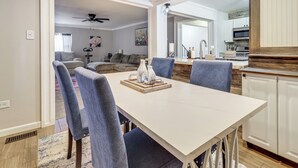 Uma sala de jantar com uma mesa branca, cadeiras azuis e um ventilador de teto.