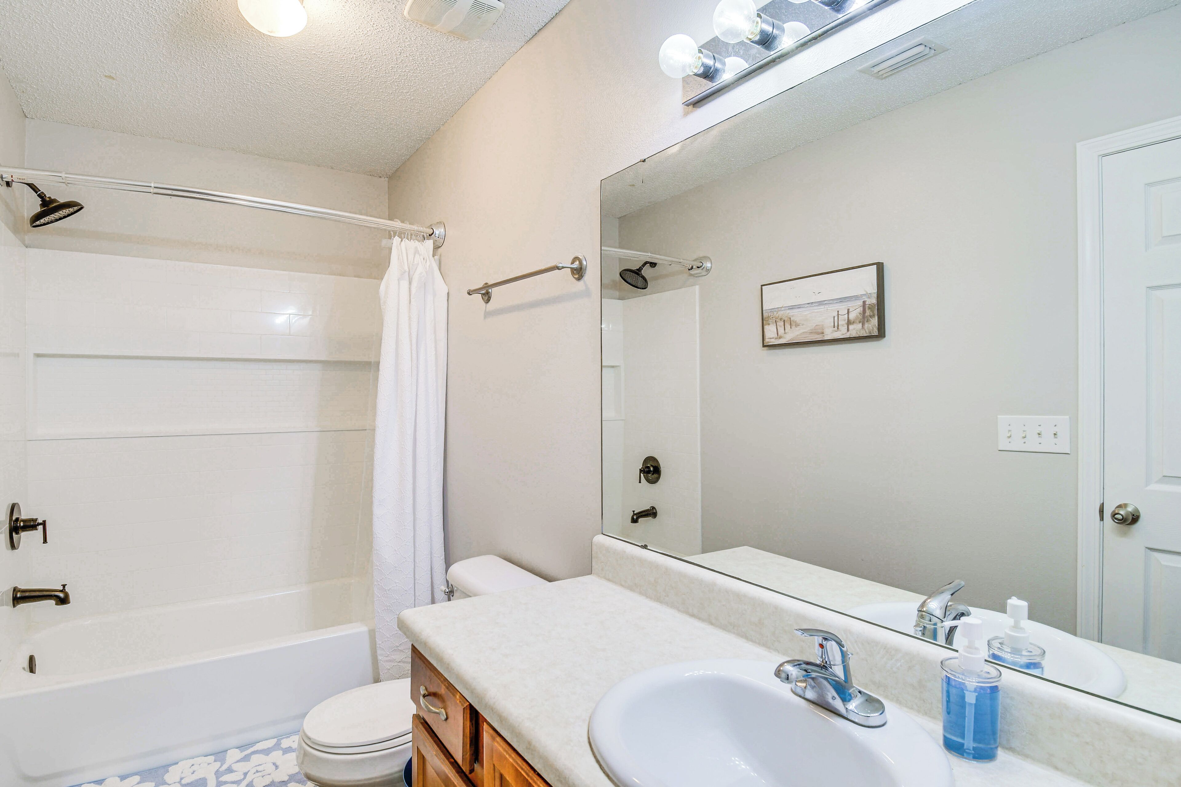 A bathroom with a bathtub, toilet, sink, and a large mirror.