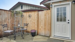 A wooden fence, a white door, a metal table with chairs, and a potted plant.
