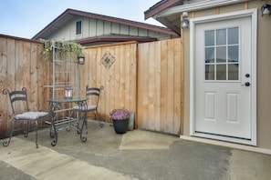 A wooden fence, a white door, a metal table with chairs, and a potted plant. - 2-unit Family Combo, Walk to Downtown Sequim! (Sequim)
