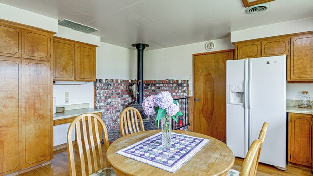 A kitchen with wooden cabinets, a refrigerator, a sink, and a dining table with chairs.