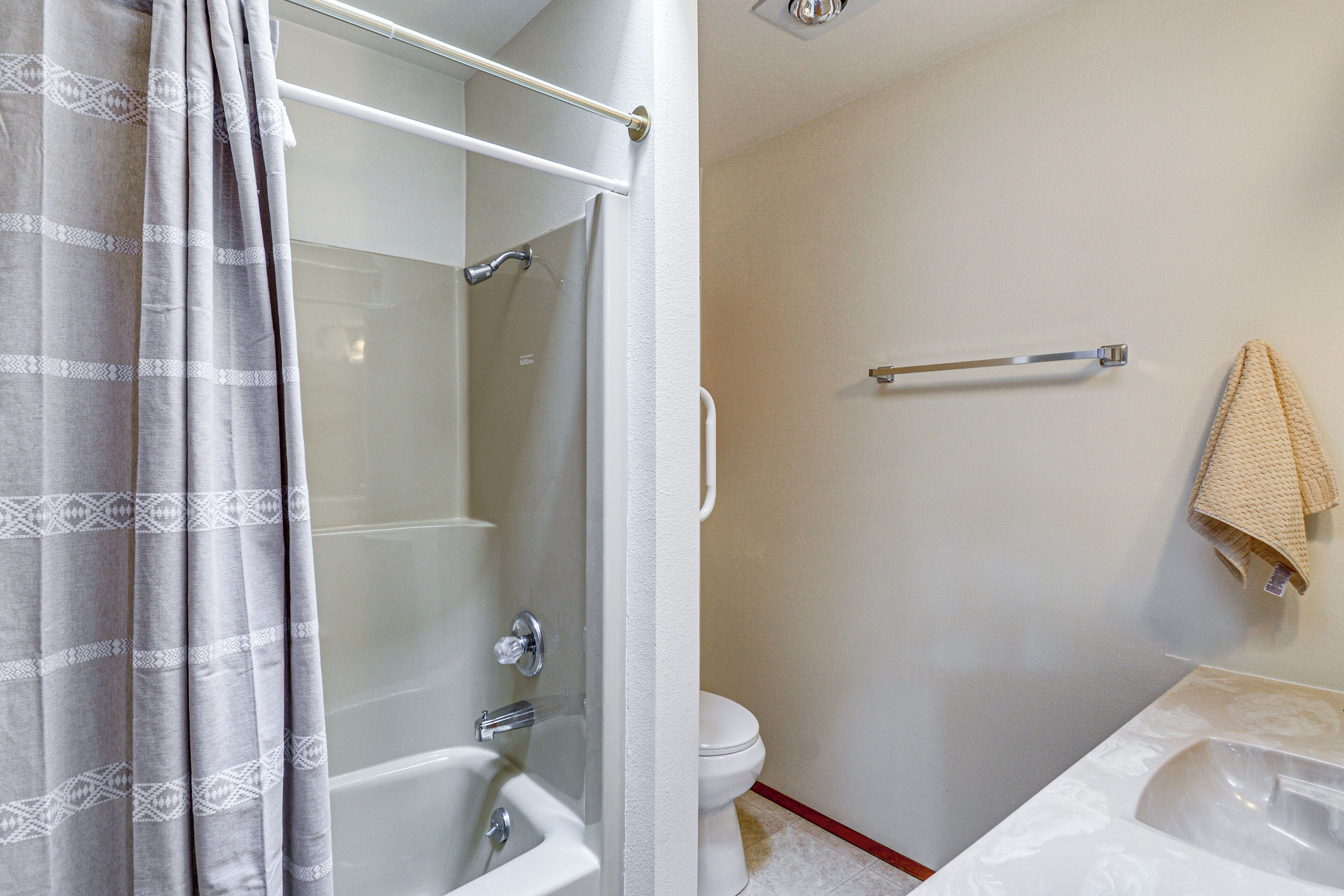 Un baño con cabina de ducha de vidrio, bañera blanca, inodoro y barra para toallas.