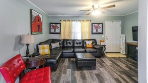 A living room with a sectional sofa, a red chair, a lamp, and a ceiling fan. - 1 Mi to Dtwn! Quaint Vidalia Getaway w/ Patio (Vidalia)