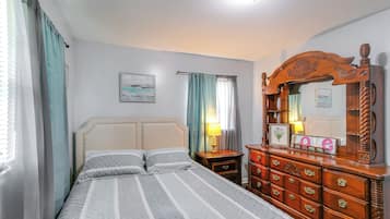 A bedroom with a bed, a dresser, a nightstand, a lamp, and a mirror.