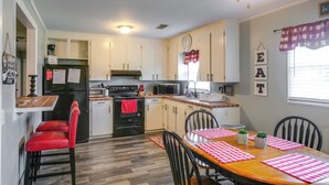 A kitchen with a dining table, chairs, a refrigerator, stove, microwave, and cabinets. - 1 Mi to Dtwn! Quaint Vidalia Getaway w/ Patio (Vidalia)