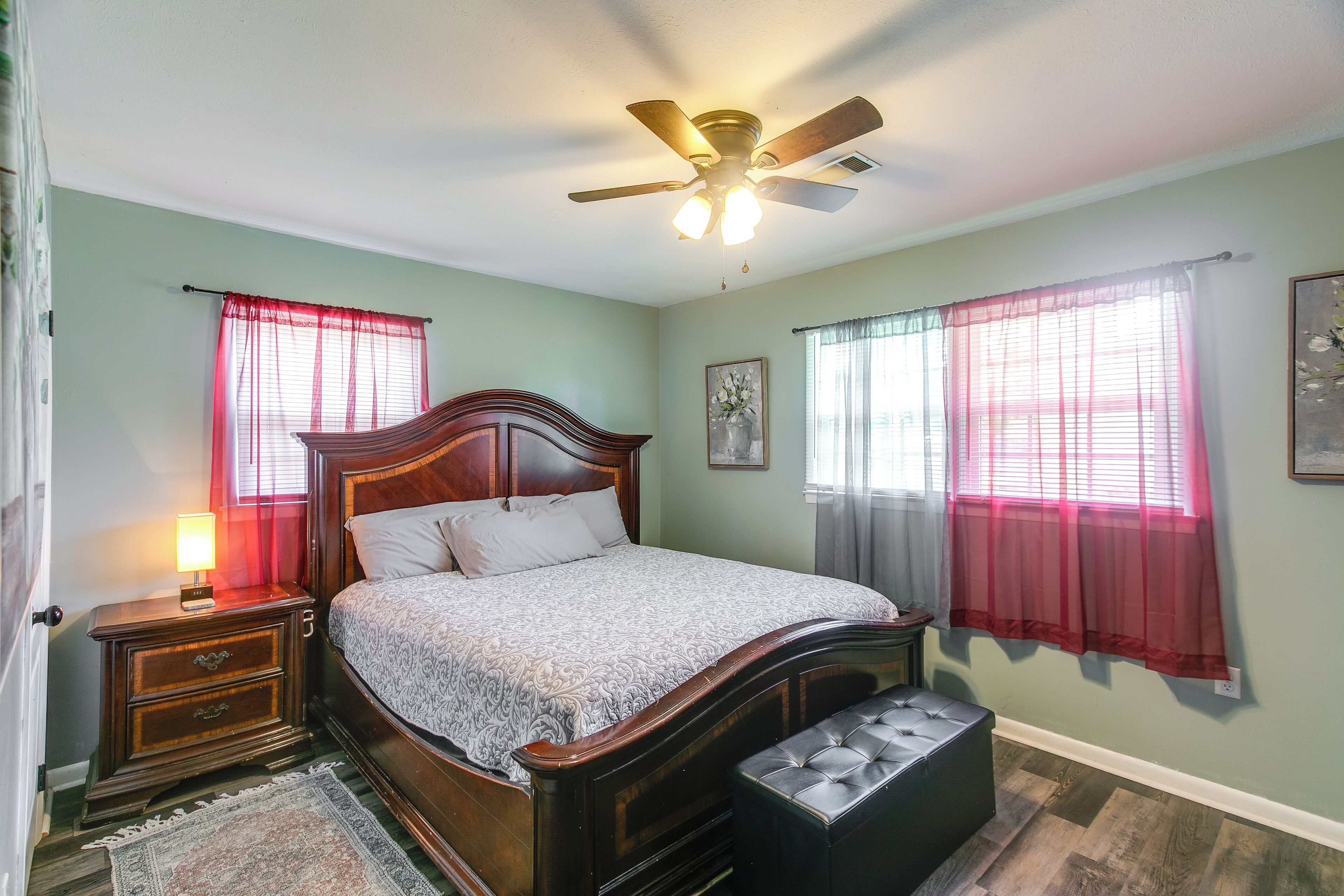 A bedroom with a bed, nightstand, bedside lamp, and a ceiling fan.