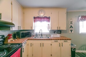 Una cocina con estufa, microondas, lavaplatos y armarios.