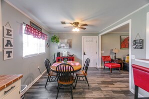 A dining area with a round table, four chairs, a ceiling fan, and a window with blinds.