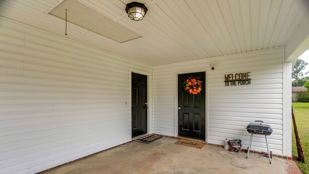 A porch with a black door, a welcome sign, a wreath, and a grill. - 1 Mi to Dtwn! Quaint Vidalia Getaway w/ Patio (Vidalia)