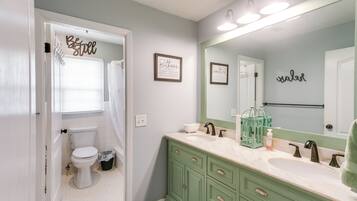 A bathroom with a toilet, sink, vanity, and a mirror.