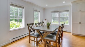 A dining room with a wooden table and chairs, large windows, and white cabinetry. - Serene & Sleek Family Retreat w/ Office in Shirley (Shirley)
