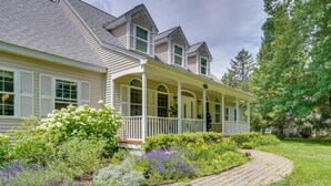 A two-story house with a covered porch, a brick pathway, and a variety of plants. - Serene & Sleek Family Retreat w/ Office in Shirley (Shirley)