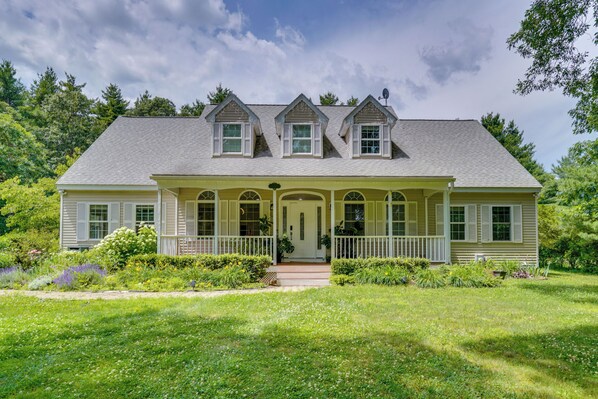 A two-story house with a front porch, a central door, and a symmetrical window arrangement.