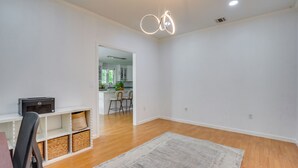 A spacious living area with a wooden floor, a white wall, a kitchen in the background, and a ceiling light fixture. - Serene & Sleek Family Retreat w/ Office in Shirley (Shirley)