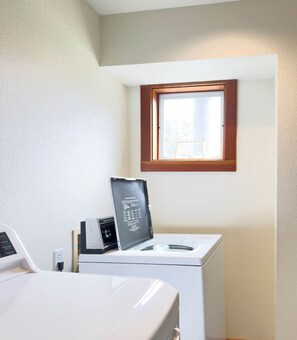 Ein Waschraum mit Waschmaschine, Trockner und einem Fenster über dem Trockner.