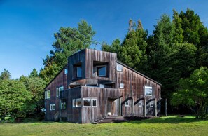 Ein modernes Holzhaus mit mehreren Ebenen, großen Fenstern und einer Treppe, die zum Eingang führt.