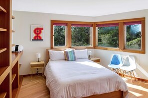 A bedroom with a large bed, two bedside tables, a chair, and a window with a view of trees. - Mistral TOT # 4838: 3  BR, 2.5  BA House in The Sea Ranch, Sleeps 6 (The Sea Ranch)