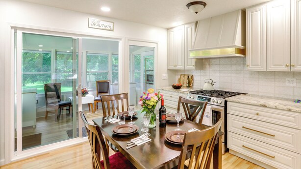 A dining room with a table set for four, a vase with flowers, and a bottle of wine. - Explore Oberlin! Home 1 Mi to Main Street & Campus (Oberlin)