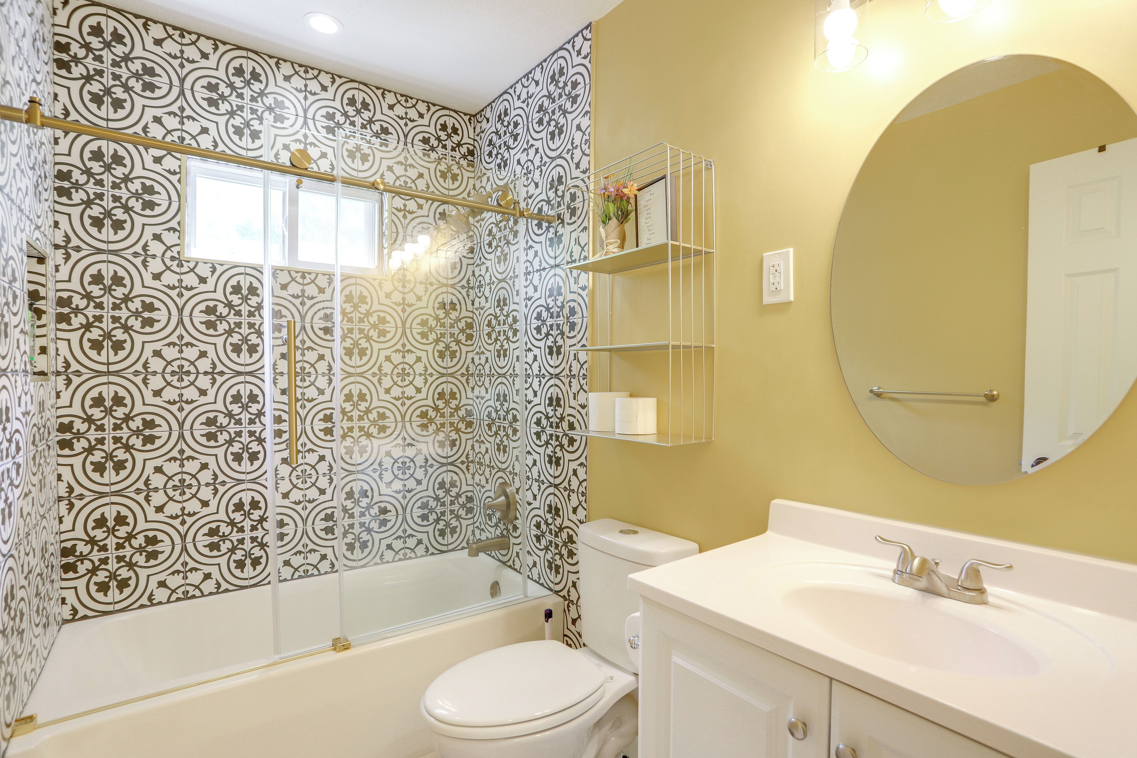A bathroom with patterned tiles, a bathtub, a toilet, a sink, and a mirror.