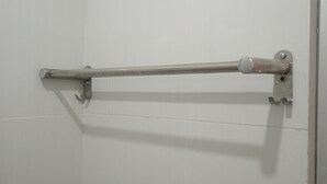 Ein Badezimmer mit weißen Fliesen, einem Metallhandtuchhalter und einer Tür.