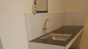 Eine kleine Küchenzeile mit Spüle, Arbeitsplatte und einem kompakten Kühlschrank.