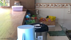Eine Küchenarbeitsplatte mit einem weißen Wasserkocher, einem Edelstahl-Reiskocher und einem Kunststoffbehälter.