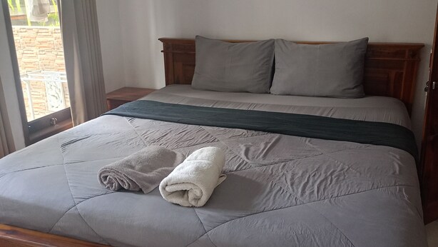 Ein Bett mit gesteppter Bettdecke, Kissen und einem zusammengerollten Handtuch.