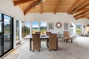 A dining area with a wooden ceiling, large windows, and a view of the outdoors. - Crows Nest TOT #1952 (The Sea Ranch)