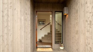 A wooden interior hallway leading to a carpeted staircase with a door and a small rug on the floor. - Crows Nest TOT #1952 (The Sea Ranch)