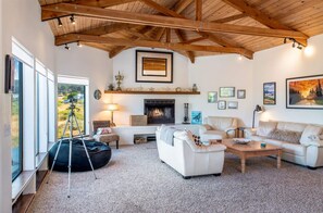 Ein großzügiger Wohnraum mit Kamin, weißen Sofas, einem Couchtisch und einem Sitzsack.