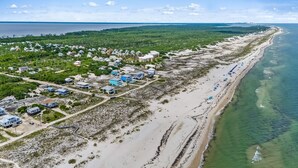 Luchtbeeld van een kustgebied met huizen, een strand en een helder uitzicht op de oceaan.