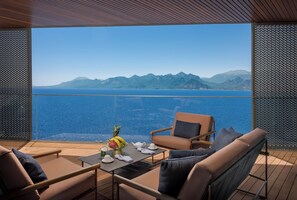 A balcony with a table set for two, a chair, and a view of the sea and mountains. - Divan Talya (Antalya)
