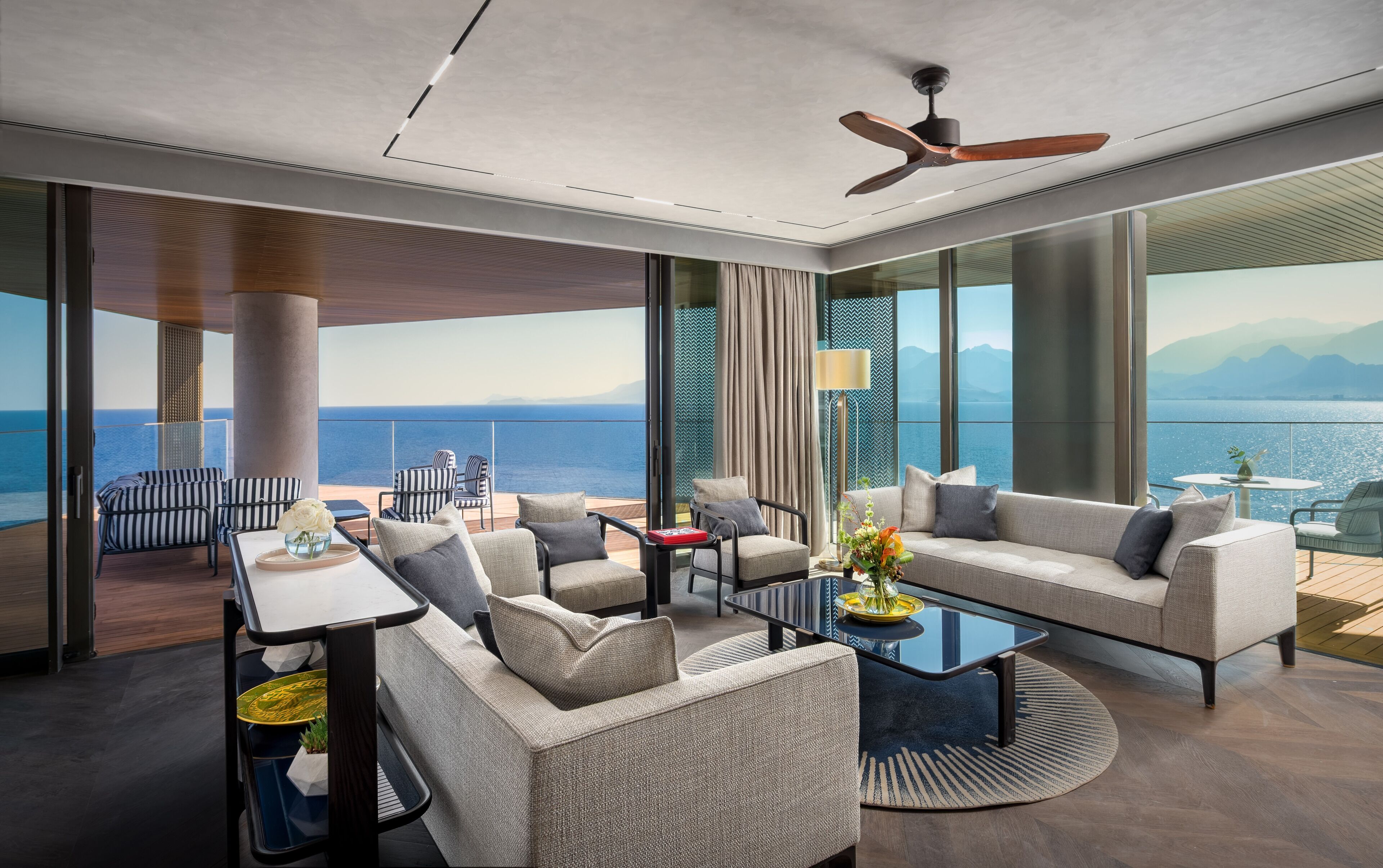 A modern interior with a sofa, chairs, a coffee table, and a view of the sea.
