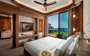 Een hotelkamer met een bed, een bureau, een televisietoestel en uitzicht op zee.