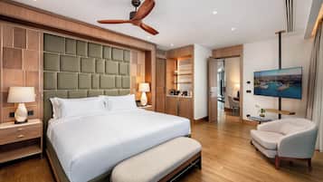 Habitación de hotel con una cama grande, ventilador de techo, televisor y zona de estar.
