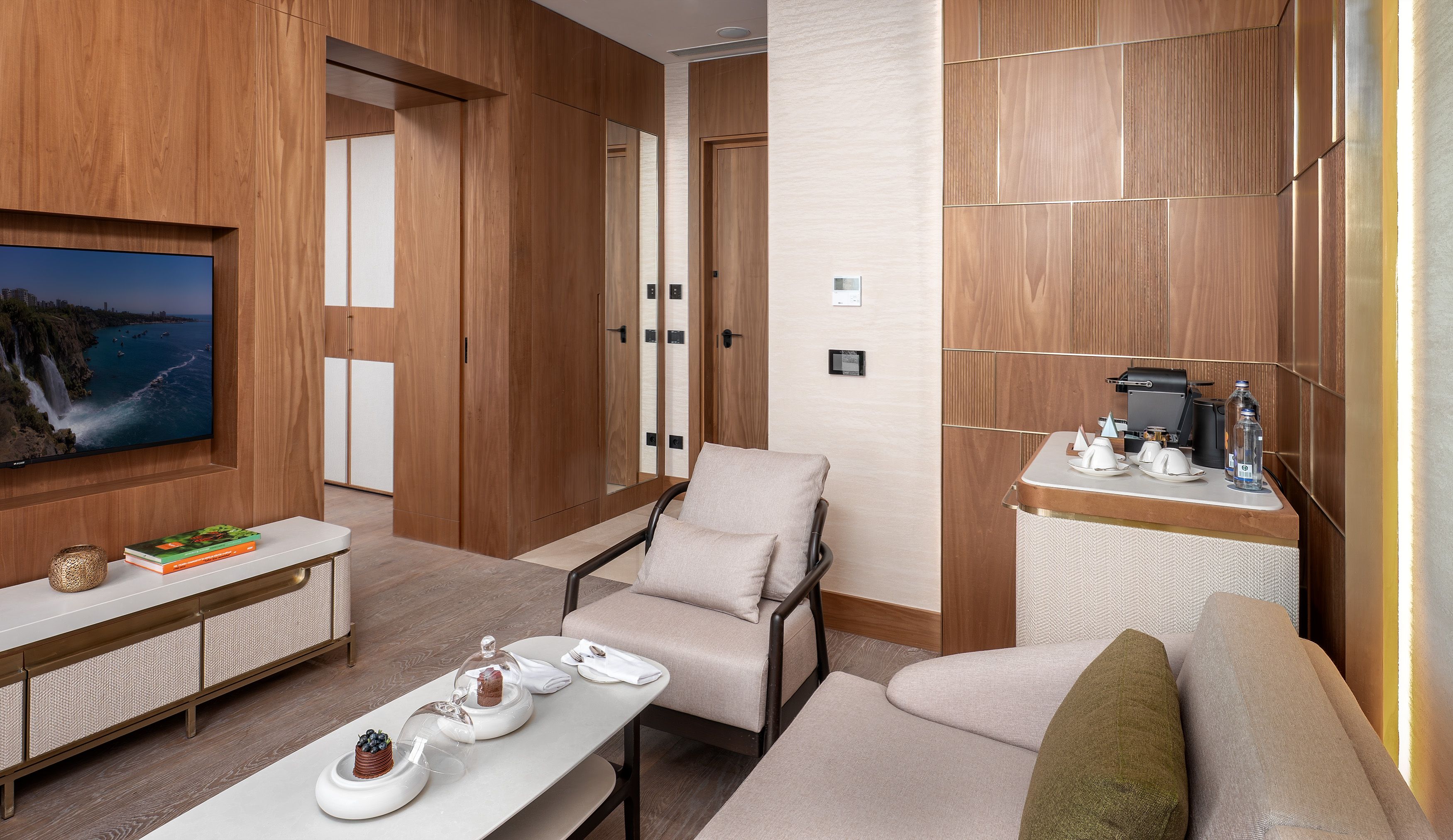 A modern living room with a television, seating, a coffee station, and wooden paneling.