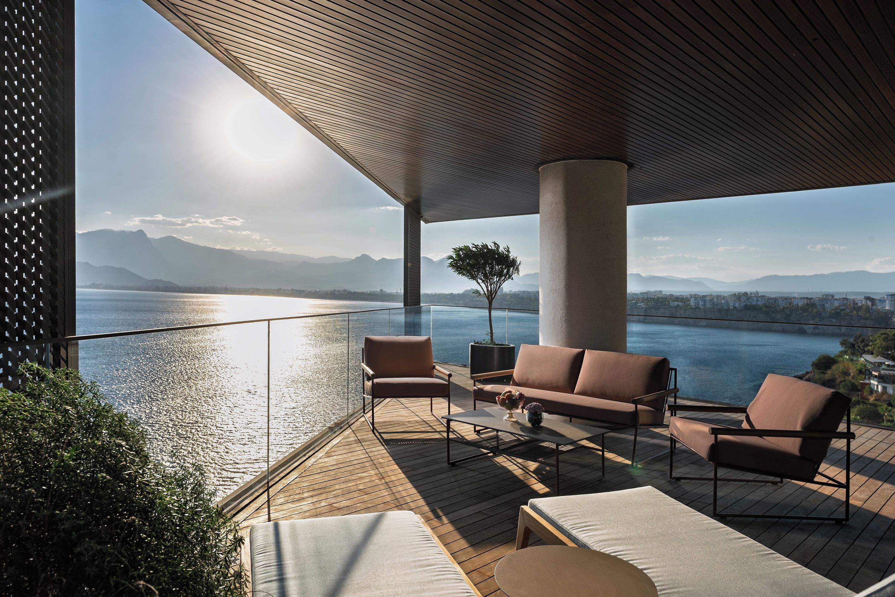 A modern outdoor seating area with a view of a body of water and distant mountains.
