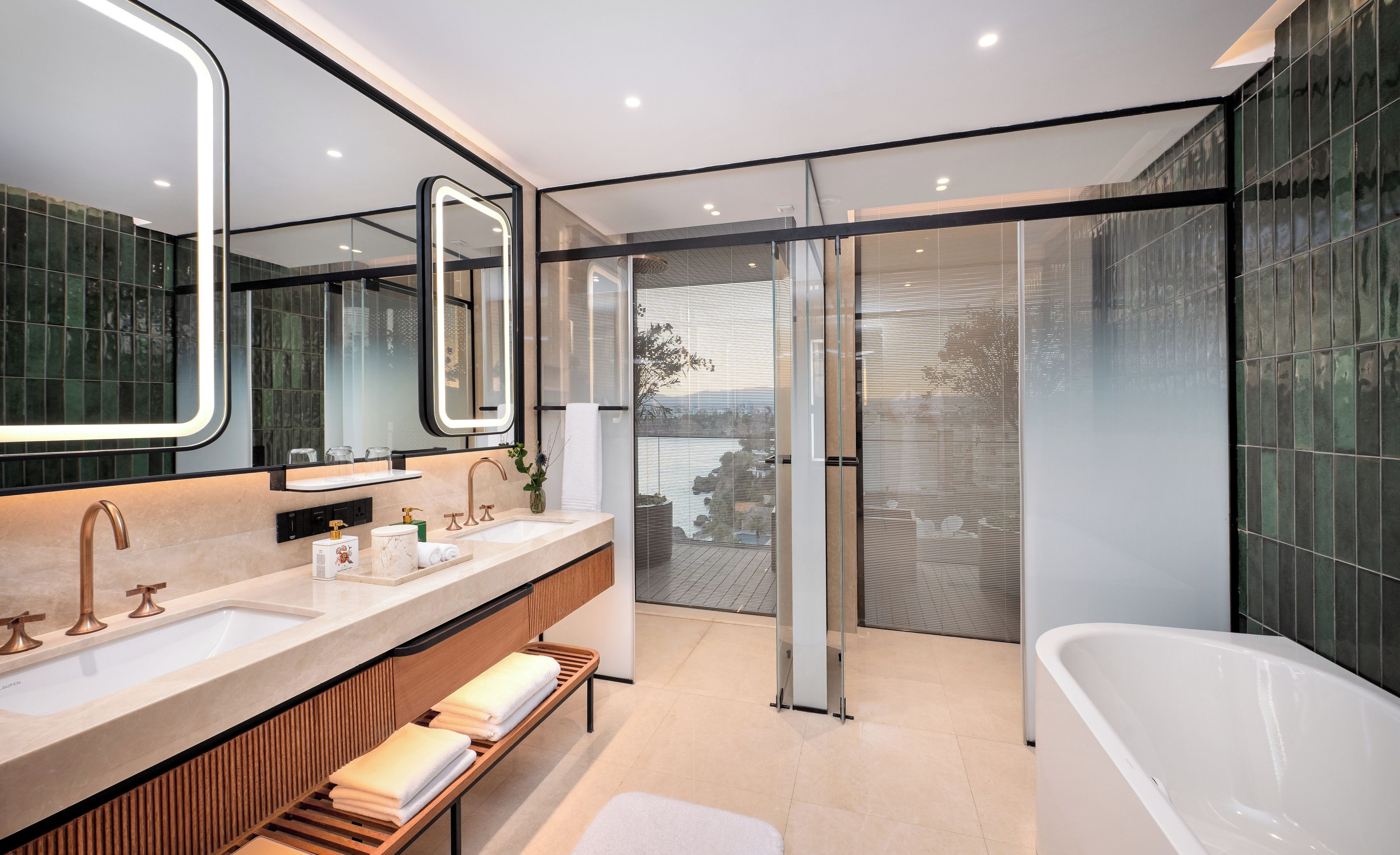 A modern bathroom with a large mirror, dual sinks, a bathtub, and a glass shower enclosure.