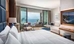 A hotel room with a bed, a sofa, a small table, and a large window offering a view of the sea. - Divan Talya (Antalya)