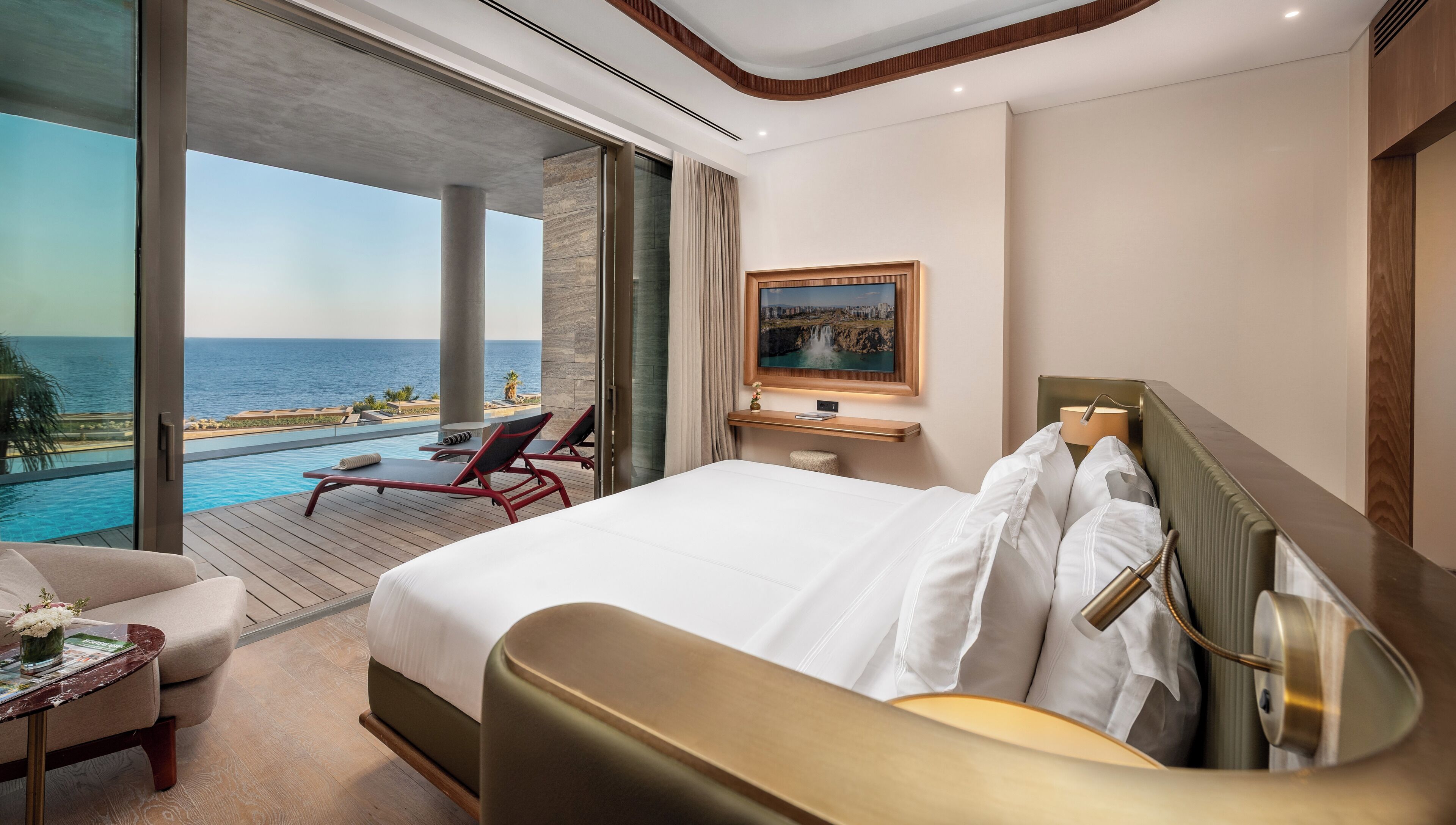 Ein Hotelzimmer mit einem großen Bett, Meerblick, einem Pool und einem Essbereich.