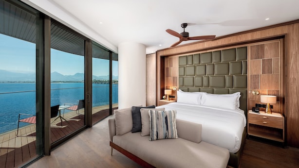 A modern hotel room with a large bed, a balcony with a view of the sea, and a ceiling fan. - Divan Talya (Antalya)