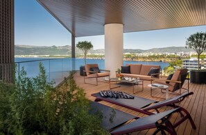 Een terras met tuinmeubilair, uitzicht op de zee en een stadsbeeld op de achtergrond.