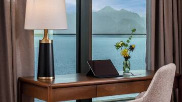 Una habitación de hotel con escritorio, computadora portátil, lámpara y un jarrón con flores.