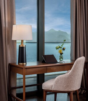 A hotel room with a desk, a laptop, a lamp, and a vase with flowers. - Divan Talya (Antalya)