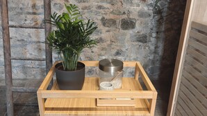 Une étagère en bois sur laquelle sont posés un pot de fleurs, un récipient en métal et des serviettes.